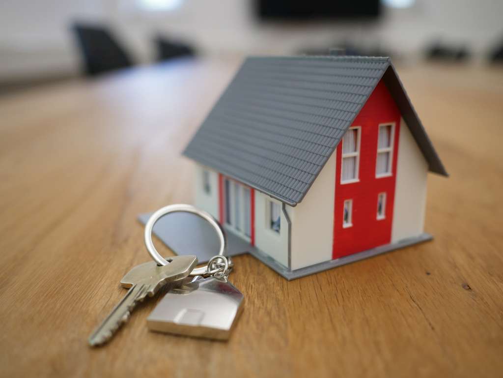 Une maison miniature et des clés sur un contrat